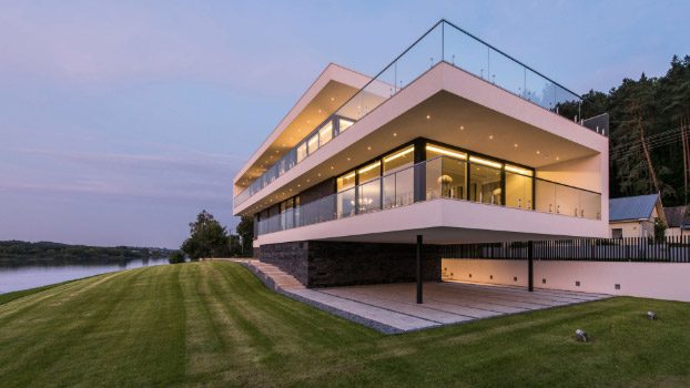 A moradia contemporânea recortada contra um céu rosado ao fim da tarde