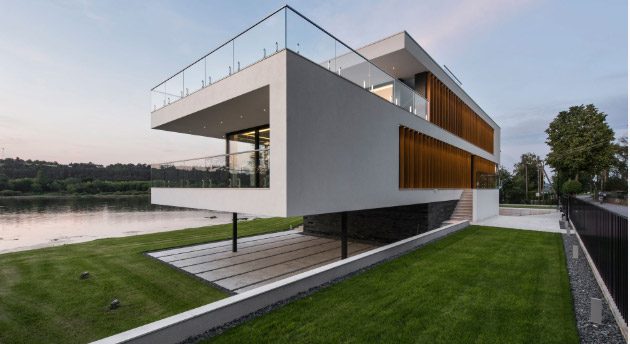 Fachada lateral da mesma moradia contemporânea, vista de dia, com revestimento em pedra no piso inferior